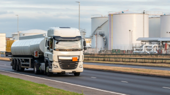 Tanker truck in motion on the road with oil depot in the background