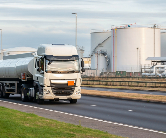 Tanker truck in motion on the road with oil depot in the background