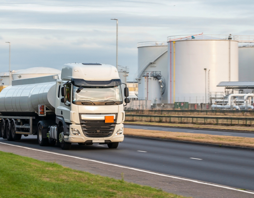 Tanker truck in motion on the road with oil depot in the background